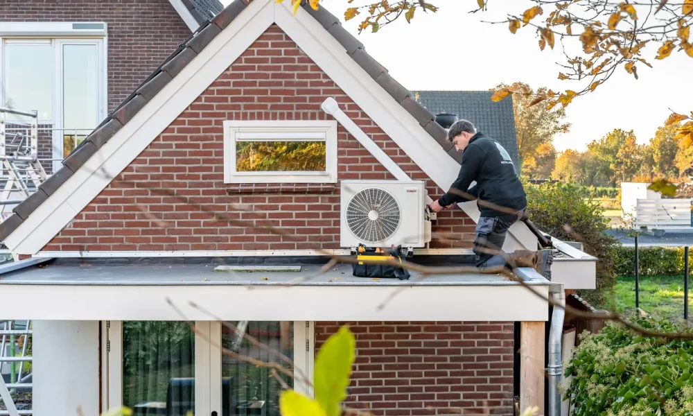 Monteur installeert airco buitenunit aan woning